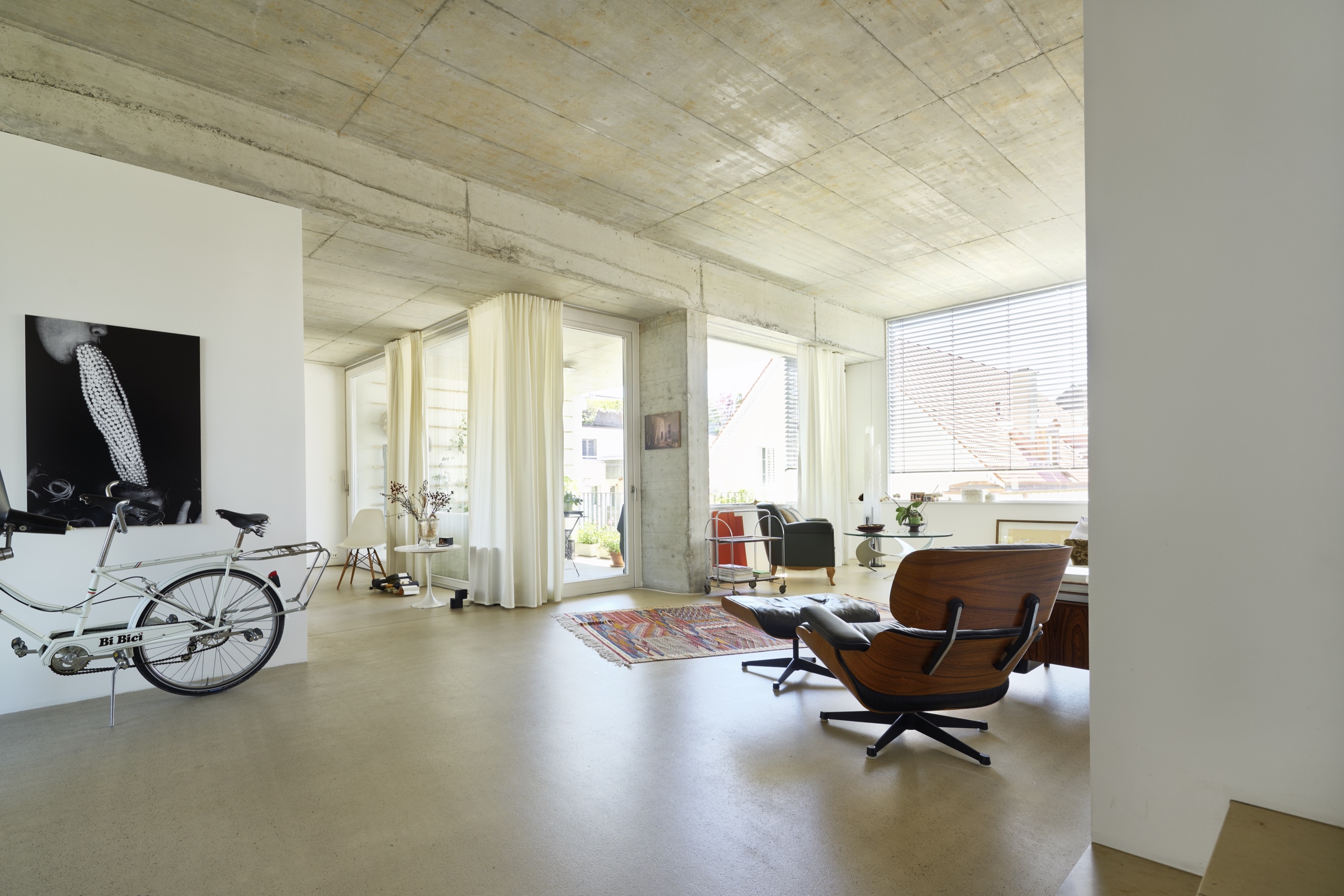 Wohnraum mit Betondecke, Eames Lounge Chair und Velo