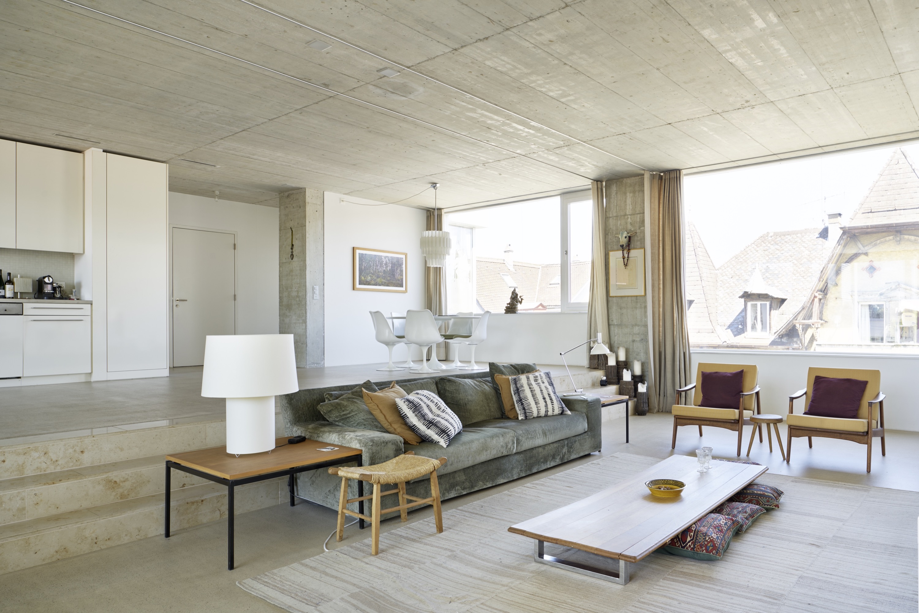 Wohnraum mit Sofa, Esstisch und Blick auf die Dächer